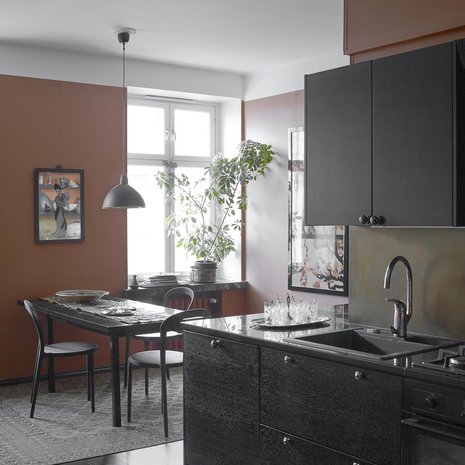 Keittiön seinien  väriksi Marita valitsi terrakotan. Hän on mieltynyt luonnonvärein värjättyihin afgaanimattoihin, joiden rauhalliset värit sopivat kellertäviin suomalaisiin puulattioihin ja ennen kaikkea tämän keittiön mustaksi maalattuun lankkulattiaan.