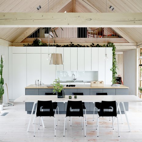 Talo on yhtä suurta tilaa, josta seinin on rajattu vain makuuhuoneet ja työhuone. Mathias suunnitteli suuret ikkunat ja lasiovet niin, että luonto olisi läsnä kotona mahdollisimman mutkattomasti. Keittiöön hän hankki Iskun kaapistot ja rakensi lattialankuista kolmimetrisen pöydän, jonka ympärillä on kymmenen vuotta sitten hankitut Piiroisen Arena-tuolit.