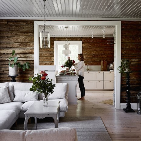 Koko alakerta on avointa tilaa. Hirsiseinät löytyivät kerroksien alta, ja oli selvää, että ne jätettiin näkyviin. Pellavatyynyt Granit, valaisin Doctor Design ja kukat kukkakauppa Verona.