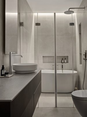 Kauniit pintamateriaalit ja harkittu valaistus luovat tilan, jossa on hyvä olla.Riittävän pieni amme löytyi Laattapisteen valikoimista, samoin kauniit hiekkakiveä muistuttavat laatat. Pienet syvennykset seinäpinnoissa lisäävät jonkin verran kuluja, mutta tuovat paljon käyttömukavuutta.