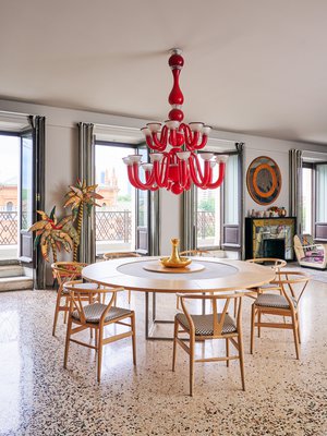 [Kuvateksti] Y-tuolien skandinaavinen tyyli sopii mittatilaustyönä valmistetun pöydän kivi- ja puupintoihin. Punainen katto-kruunu on Murano-lasia. Lattia on Ottavio Missonin suunnittelema.