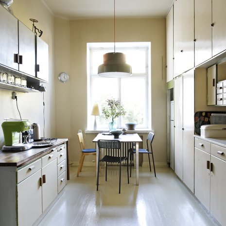 Keittiö on yhä alkuperäisessä asussaan. Seinät, katto ja lattia maalattiin kaikki samalla kellertävällä sävyllä kuin kaapit, jotta tunnelmasta tuli harmoninen ja mittasuhteet hämärtyvät. Ainoat uudet hankinnat asuntoon ovat Ateljé Lyktanin Bumling-riippuvalaisin sekä Ikean mustat pikkutuolit.