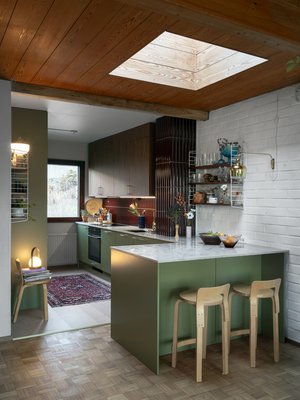 Niemekettä valaisee kattoikkuna, jonka alla oli alun perin ruokapöydän paikka. Niemekkeessä on kaappitilaa sekä keittiön että olohuoneen puolella. Liesituuletin on piilossa yläkaapissa. Yläkaappien ovet ovat täyspuuta, ne on valmistanut Mittapuu. Kalkkikivitaso on Tuliven Jura Grey.