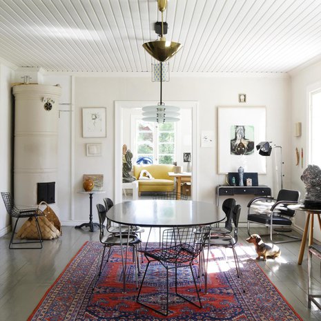 Ruokailuhuone on keskellä alakertaa, ja sieltä on näkymät työhuoneeseen ja olohuoneeseen. Koska talon isännällä on useita kattovalaisimia, hän sijoitti kolme niistä Fritz Hansenin ruokapöydän päälle. Pöydän ympärillä on Arne Jacobsenin Muurahaistuolit ja Knollin Bertoia-tuolit. Jalkalamppu on Yrjö Kukkapuron suunnittelema.