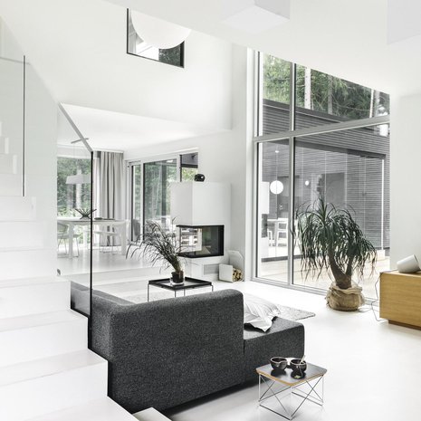 Takkatulesta  voi nauttia  monesta eri suunnasta. Schmidin Ekko U55 -kiertoilmatakka maalattiin seinien väriseksi. Alakerran mikrosementtilattia Pandomo floor on luonnonvalkoinen. Isot ikkunapinnat aurinkosuojakäsiteltiin, jolloin auringonvalo ei paista sisään liian kuumasti. Portaiden  lasikaiteet ovat Zeta Designista.