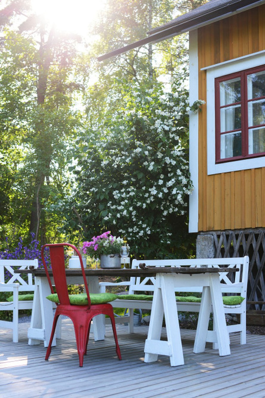 Takon edess&auml; on iso terassi, jossa on itse nikkaroitu reilu pukkijalkap&ouml;yt&auml; ja Skagerakin Drachman-penkit.