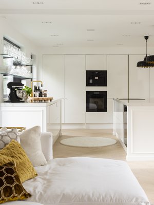 Kun väliseinät purettiin, piti suureen tilaan integroida uusia tukirakenteita. Keittiön toimitti Novart Espoo. Takaseinän korkeissa kaapeissa on aamiaiskaappi kahvikoneineen sekä viinikaappi. Saarekkeen syvyydeksi päätettiin 130 cm. Leveydeltään se on kolmemetrinen, sillä säilytystila haluttiin maksimoida. Myös saarekkeen baarituolien puolella on kaappitilaa.