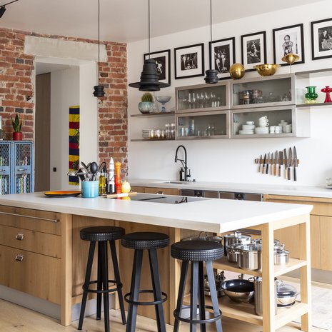 Keittiökalusteet ja baari-jakkarat ovat Scavolini Diesel Social Kitchen -mallistoa. Saarekkeen päällä olevat valaisimet puolestaan ovat Dieselin ja Foscarinin yhteistyömallistosta ja kulkeneet mukana jo kymmenen vuotta. Keittiön tasot ovat Tulikiven komposiittikvartsia. Vanhat siniset teräskaapit ovat Villen tuliaisia Yhdysvalloista.