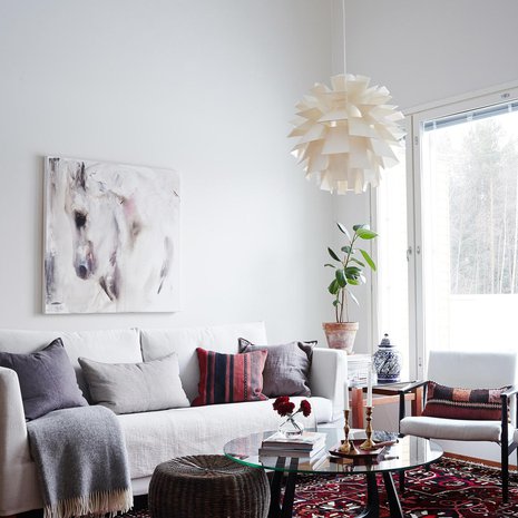 Olohuoneen matto on Carpetvistasta ja Elinan mielestä täydellinen tyydyttämään värinhimoa. HT-Collectionin sohvan ja sohvapöydän Elina hankki nettihuutokaupasta. Sohvan yllä on Katja Hannulan Heijastuksia-teos.