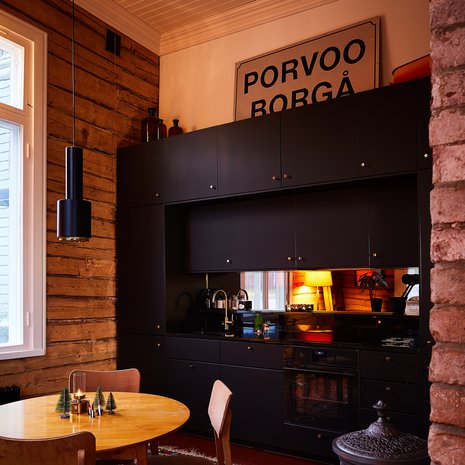 Vaikka talo on kunnostettu vanhaa kunnioittaen, keittiöön valittiin modernit, ajattoman mustat kaapistot. Keittiö on Ikean Kungasbacka ja se on valmistettu osittain kierrätetyistä muovipulloista. Välitilan pronssin sävyinen peili toistaa kauniisti vastakkaisen seinän hirsipintaa.