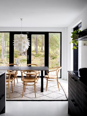 Hanna valitsi ruokatilaan suuren, mustan Muuton ruokapöydän. Tuolit ovat Tonin, ja niiden mallinumero on 30. Luonto tulee osaksi sisustusta suurien ikkunoiden kautta myös ruokatilassa. Norm 69 -valaisin on Normann Copenhagenin.