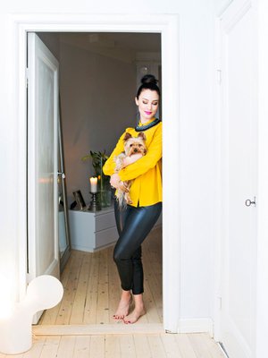 Kotiin tultuaan Noora ottaa ensimm&auml;iseksi Wallu-koiran syliin. Heti sen j&auml;lkeen h&auml;n vaihtaa ty&ouml;vaatteet mukavampiin l&ouml;k&ouml;housuihin.