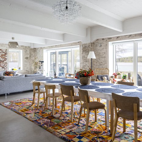 "Olohuoneen matot hankittiin vuonna 2014 Marrakechin mattobasaarista, jossa kolme miestä esitteli meille ainakin 50 mattoa. Kun iso ruokailutilan matto kannettiin esiin, olin myyty", Anu kertoo. Pitkä ruokapöytä syntyi puolivahingossa, kun 38 hengen suvun saapuessa kylään pöytää jatkettiin palasilla. Ruokailutuolit, Artek. Rottinkituoli ja jalkalamppu, Broste Copenhagen.