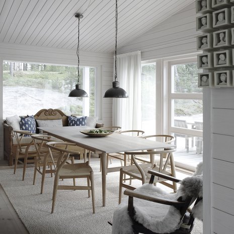 Ruokailutila on aivan keittiön kyljessä. Sisustuksen helmet ovat Hans J. Wegnerin ruokapöytä ja CH24-tuolit. Niiden kevyt rakenne ja kaunis muotoilu sopivat yhteen Matin perintökeinutuolin ja Fiskarsin antiikkimarkkinoilta ostetun talonpoikaissohvan kanssa.