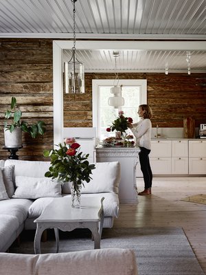 Koko alakerta on avointa tilaa. Hirsiseinät löytyivät kerroksien alta, ja oli selvää, että ne jätettiin näkyviin. Pellavatyynyt Granit, valaisin Doctor Design ja kukat kukkakauppa Verona.