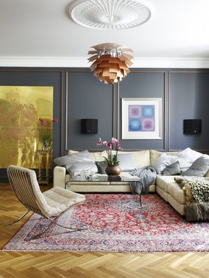 Olohuoneen seinät paneloitiin tummilla puupaneeleilla, joihin maalattiin pronssin-sävyiset koristelistat. Punasävyinen Keshan-matto ja Barcelona-tuoli ovat huutokauppalöytöjä. Lasipöytä on hankittu Vepsäläiseltä. Sohvan päällä on Victor Vasarelyn työ.