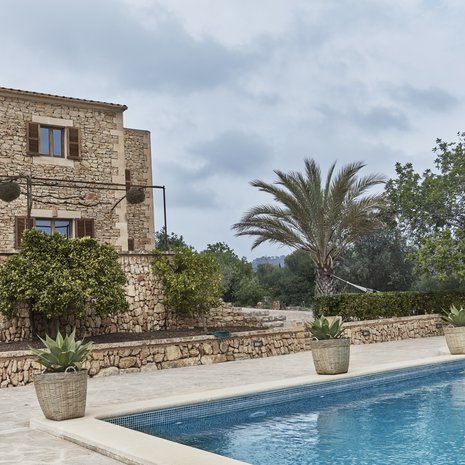 Uima-allas on ympäröity samoilla kivillä, joita on käytetty myös talon ulkopinnassa. Niin pihapiirin ilme näyttää yhtenäiseltä. Pensasaita luo suojaa peittämättä kuitenkaan näkymää.