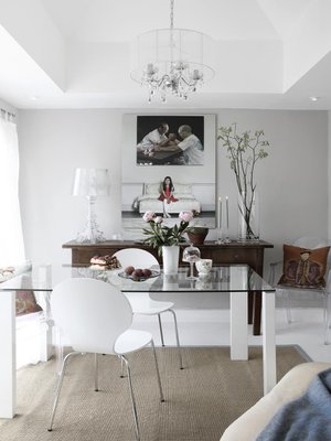 Valkoinen sisustus ja lasipöytä ovat raikas valinta pieneen ruokailutilaan. Liukuovet aukeavat terassille. Seitinohuet verhot suojaavat liialta auringolta. Sivupöydän päällä on Ferruccio Lavianin Kartellille suunnittelema Bourgie-valaisin. Läpinäkyvät tuolit ovat Kartellin Louis Ghostit.