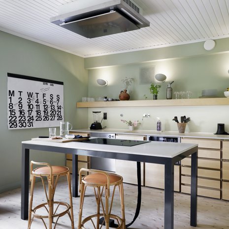 Puuseppä Pekka Koivikko valmisti keittiön mittojen mukaan koivusta. Betonitasot valmisti 16juin.com. Keittiön seinät maalattiin hengittävällä Auro-luomumaalilla. Ruokapöytämäiseen saarekkeeseen upotettiin liesitaso, jonka lattiaan johtavat sähköjohdot sukitettiin siististi pussiin. Liesituuletin sijoitettiin kattoon.