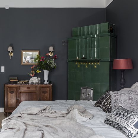 Makuuhuoneen kakluunin syvä vihreä sävy määritti muun huoneen värityksen. Marmorikantinen lipasto löytyi vanhojen tavaroiden liikkeestä. Sängyn tekstiilit luovat mielenkiintoisen pintojen yhdistelmän tummaa taustaa vasten.